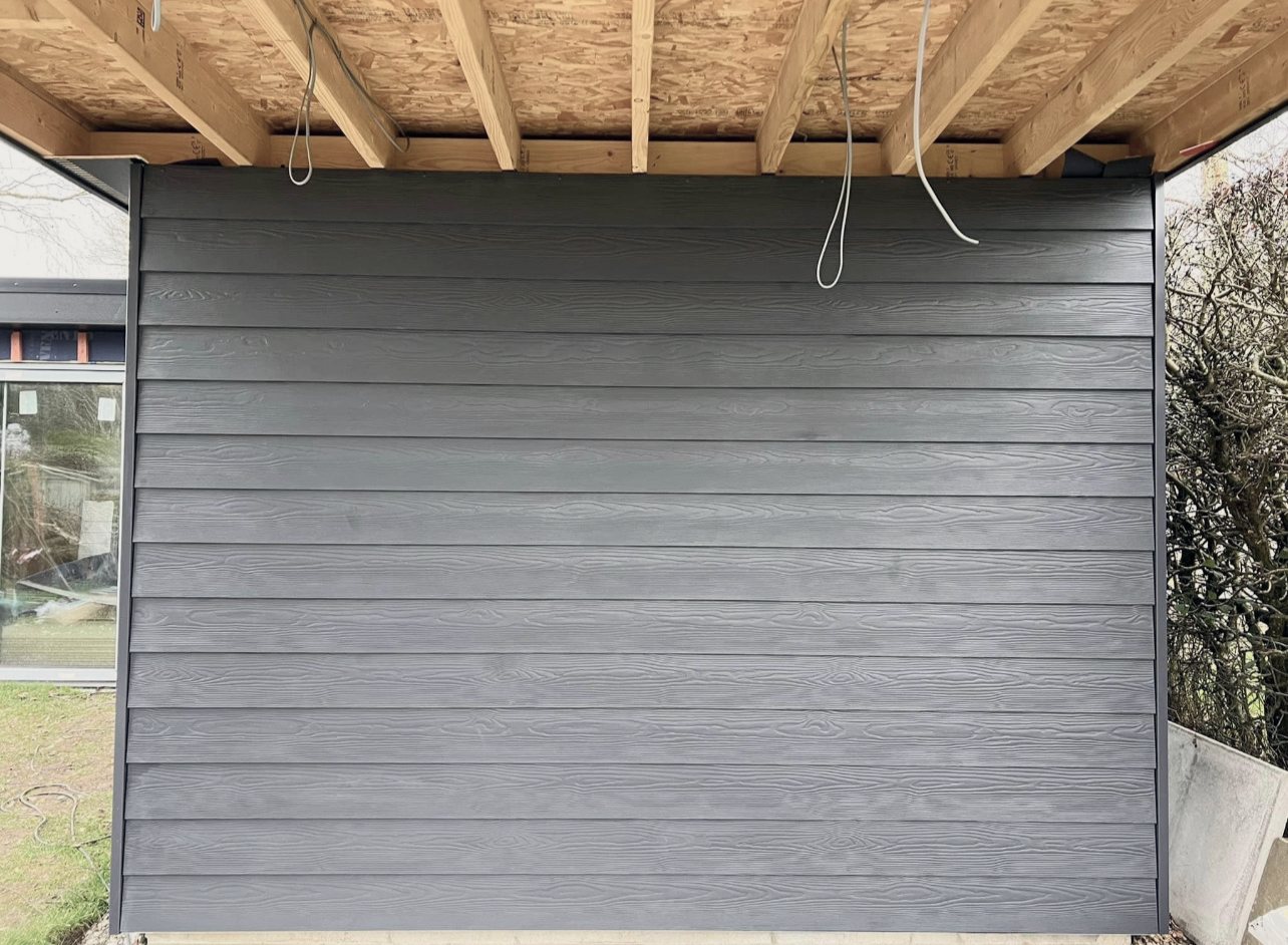 Grey weatherboard cladding on the side of a garden room, under the roof timbers