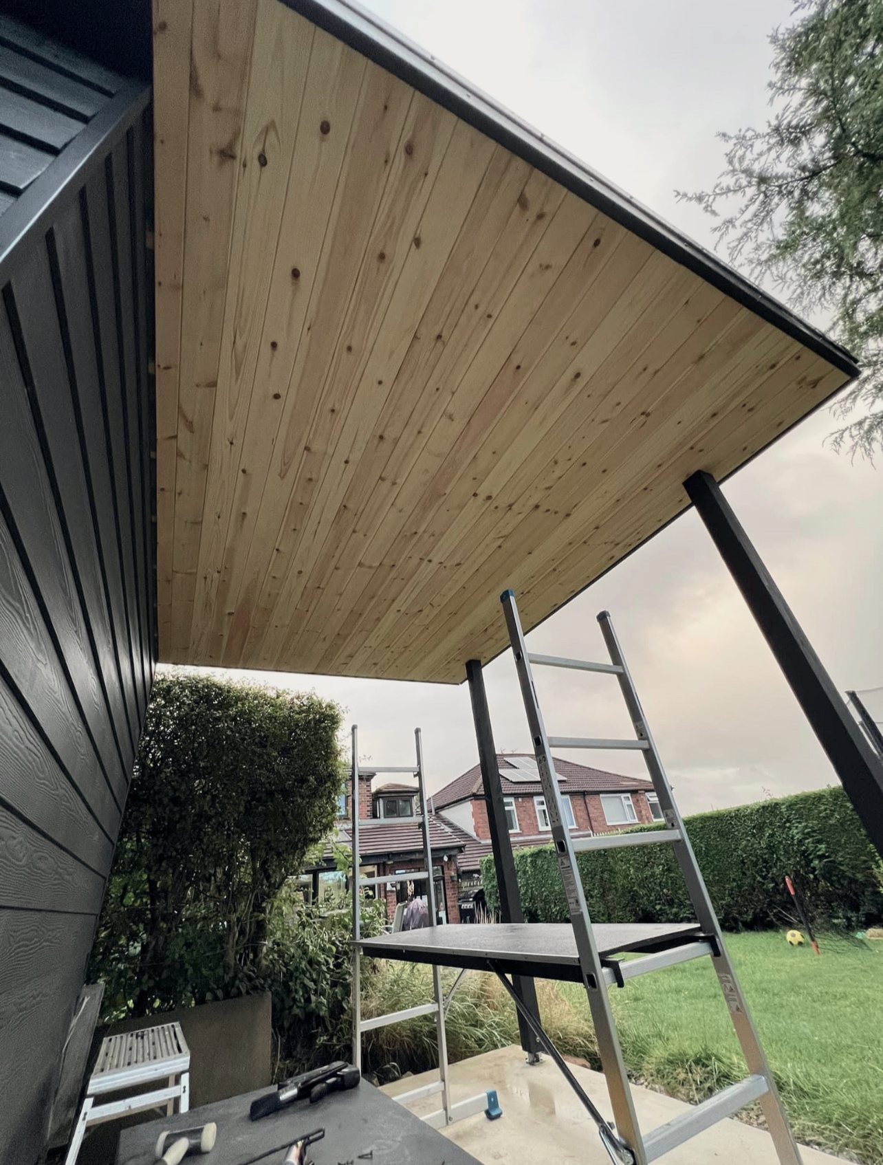 A tongue-and-groove timber soffit under the overhang of a clad garden room