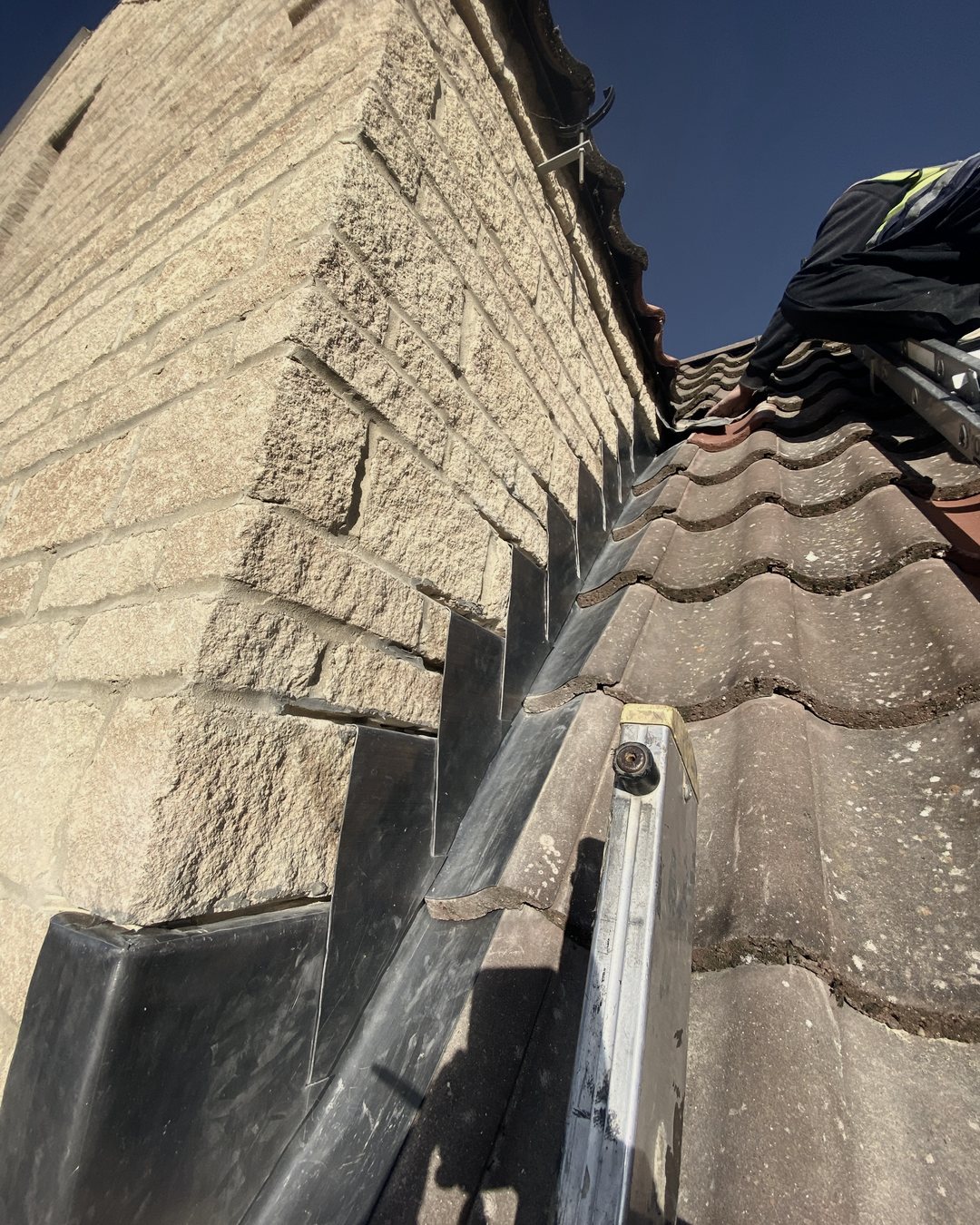 Lead step flashing running up a stone gable, seen from the roof