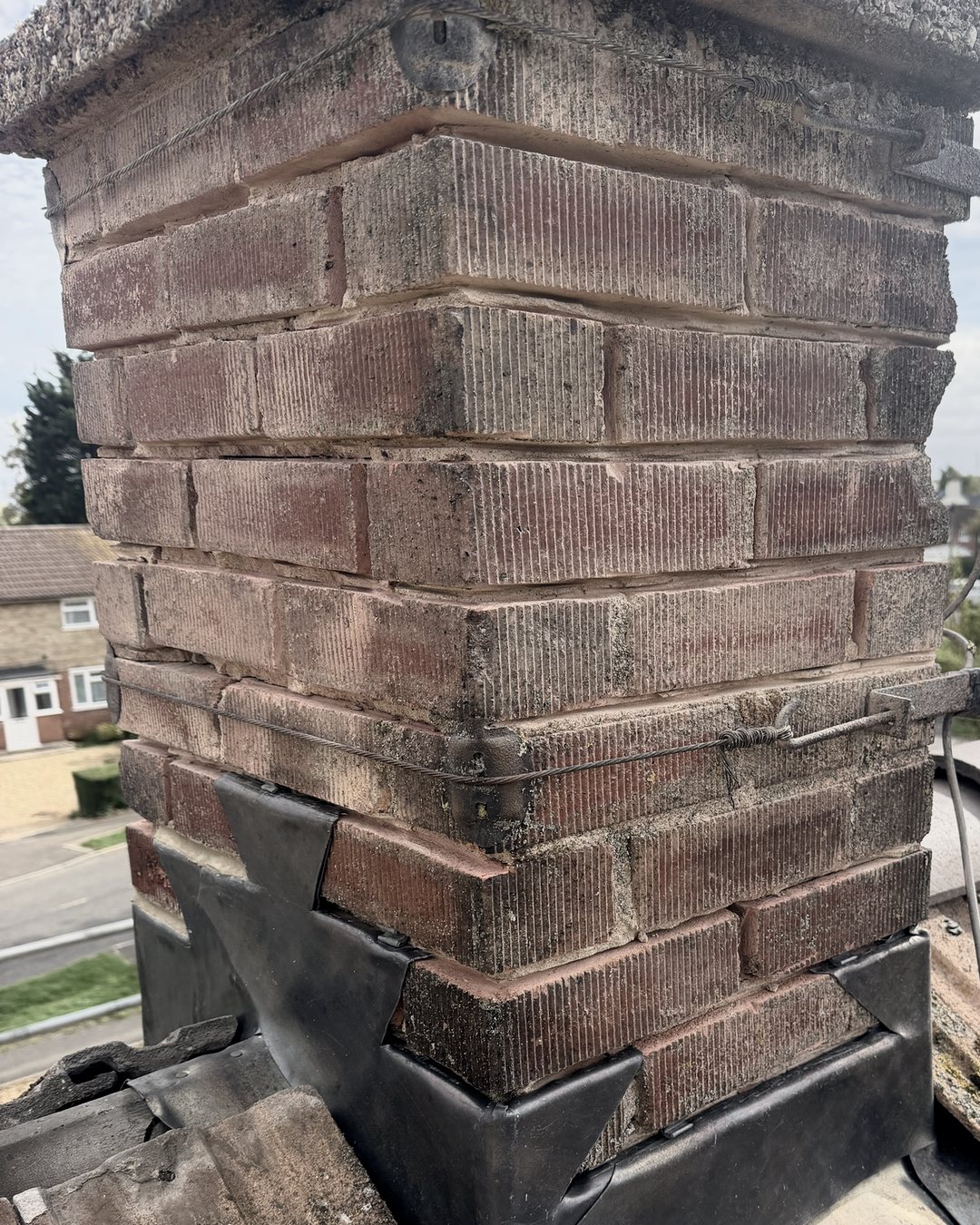 A brick chimney with new lead step flashings and apron, on a concrete tiled roof