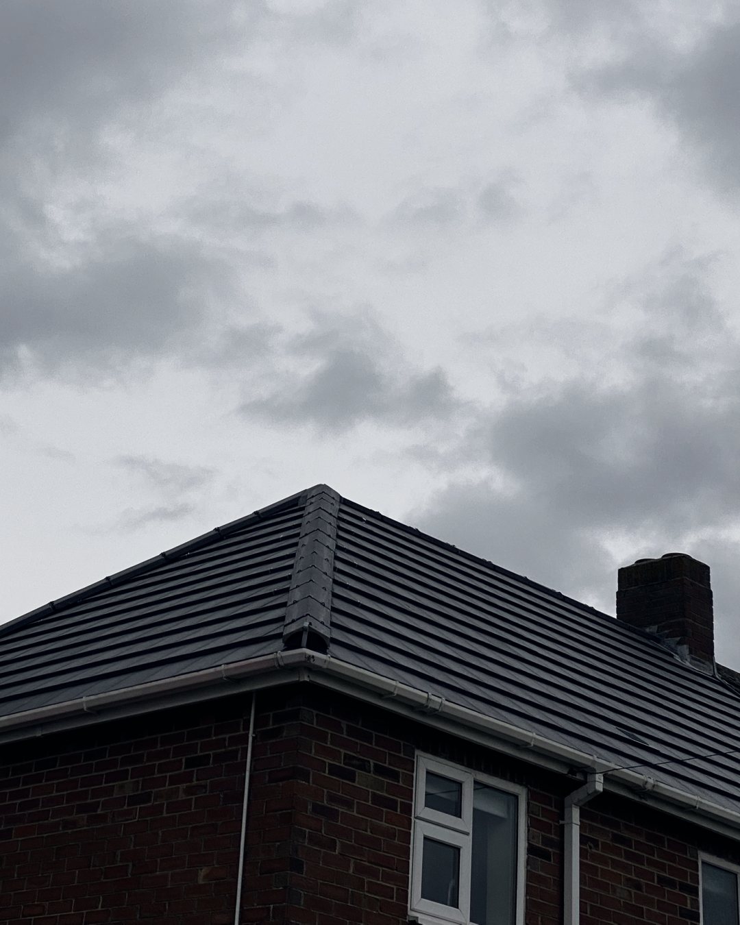 Close-up of a grey hip on the new roof running down to the corner gutter