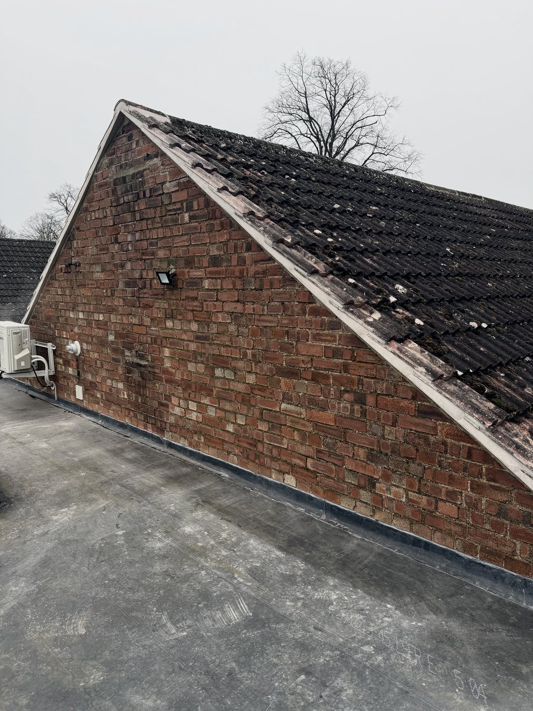 The finished verge running up the brick gable, seen from the flat roof below