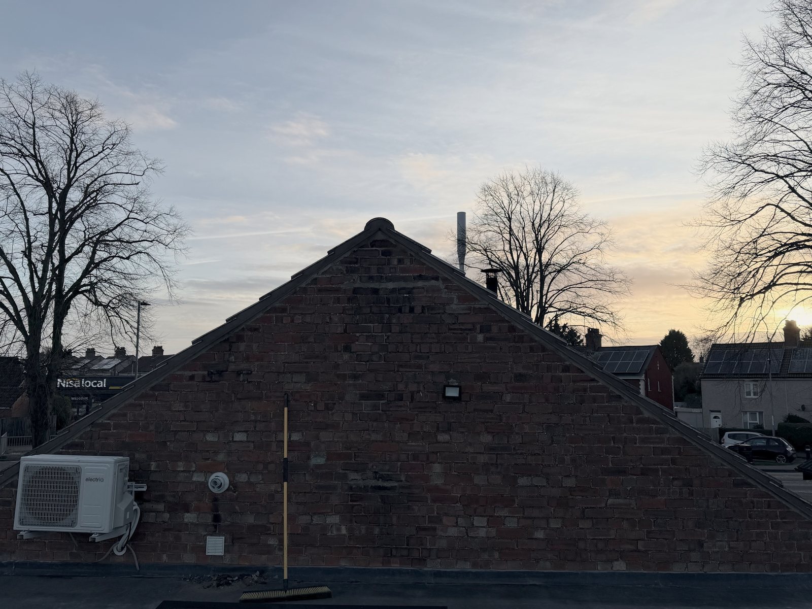 The brick gable end seen straight on from the flat roof at sunset