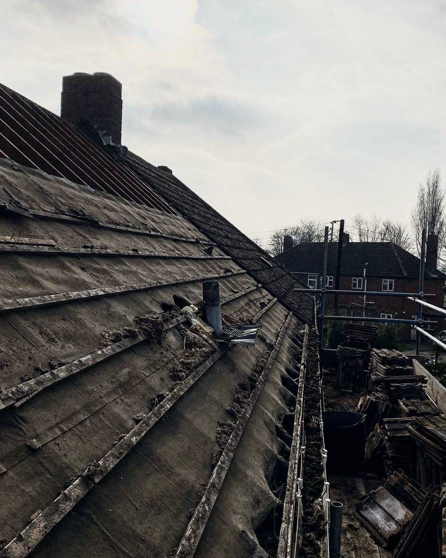 Before: roof tiles stripped off, showing the old felt and battens