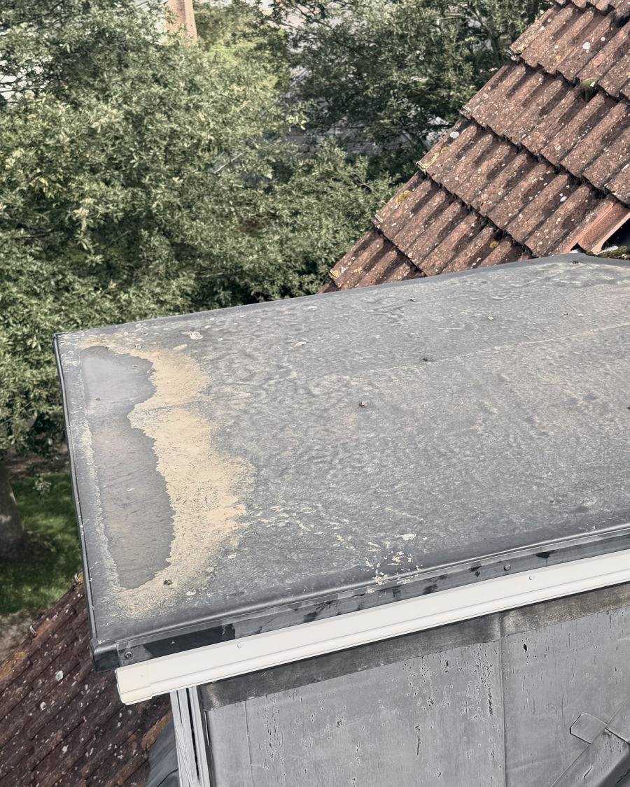 Before: worn, patched covering on a flat dormer roof
