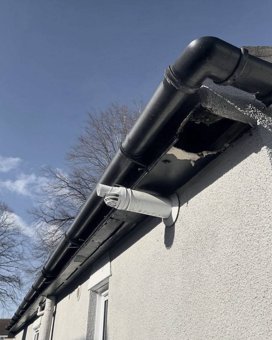 Before: a rotten soffit board with a hole behind the gutter